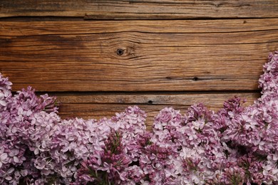 Photo of Beautiful lilac flowers on wooden table, flat lay. Space for text