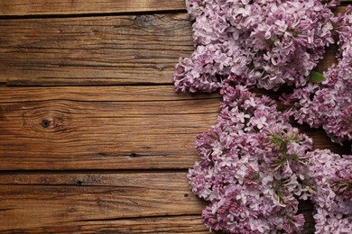 Photo of Beautiful lilac flowers on wooden table, flat lay. Space for text