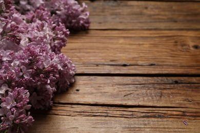 Photo of Beautiful lilac flowers on wooden table, closeup. Space for text