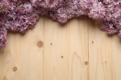 Photo of Beautiful lilac flowers on wooden table, flat lay. Space for text
