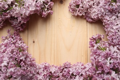 Photo of Frame of beautiful lilac flowers on wooden table, flat lay. Space for text
