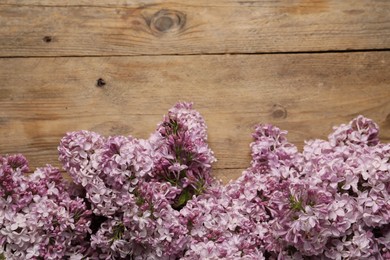 Photo of Beautiful lilac flowers on wooden table, flat lay. Space for text