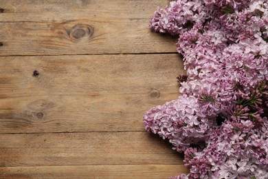 Photo of Beautiful lilac flowers on wooden table, above view. Space for text