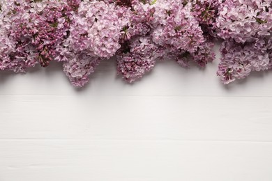Photo of Beautiful lilac flowers on white wooden table, flat lay. Space for text