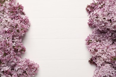 Photo of Beautiful lilac flowers on white wooden table, flat lay. Space for text
