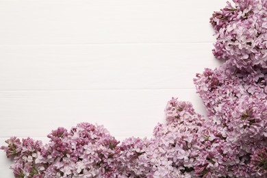 Photo of Beautiful lilac flowers on white wooden table, flat lay. Space for text