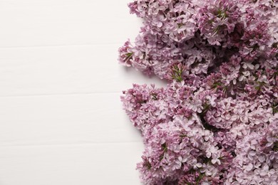 Photo of Beautiful lilac flowers on white wooden table, flat lay. Space for text