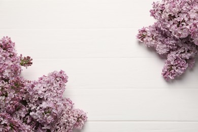 Photo of Beautiful lilac flowers on white wooden table, flat lay. Space for text