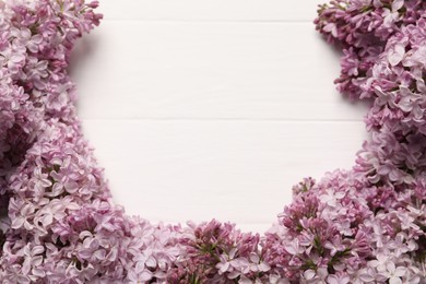 Photo of Beautiful lilac flowers on white wooden table, above view. Space for text