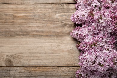Photo of Beautiful lilac flowers on wooden table, flat lay. Space for text