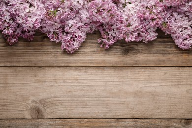 Photo of Beautiful lilac flowers on wooden table, flat lay. Space for text