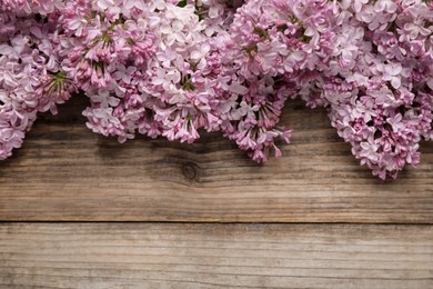 Photo of Beautiful lilac flowers on wooden table, flat lay. Space for text