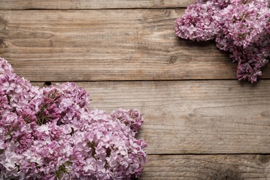 Photo of Beautiful lilac flowers on wooden table, flat lay. Space for text