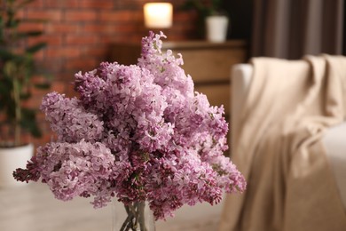 Photo of Beautiful lilac flowers in vase indoors, closeup. Space for text