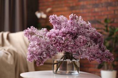 Photo of Beautiful lilac flowers in vase on table indoors