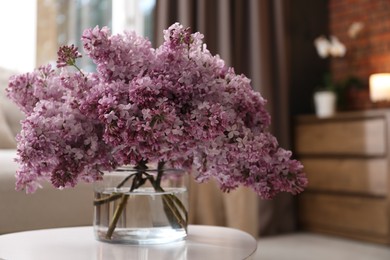 Photo of Beautiful lilac flowers in vase on table indoors