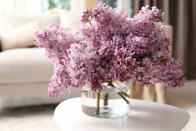 Photo of Beautiful lilac flowers in vase on table indoors
