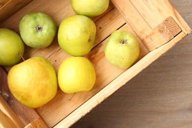 Photo of Damaged green apples in wooden crate on table, top view