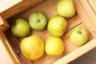 Photo of Damaged green apples in wooden crate on table, top view