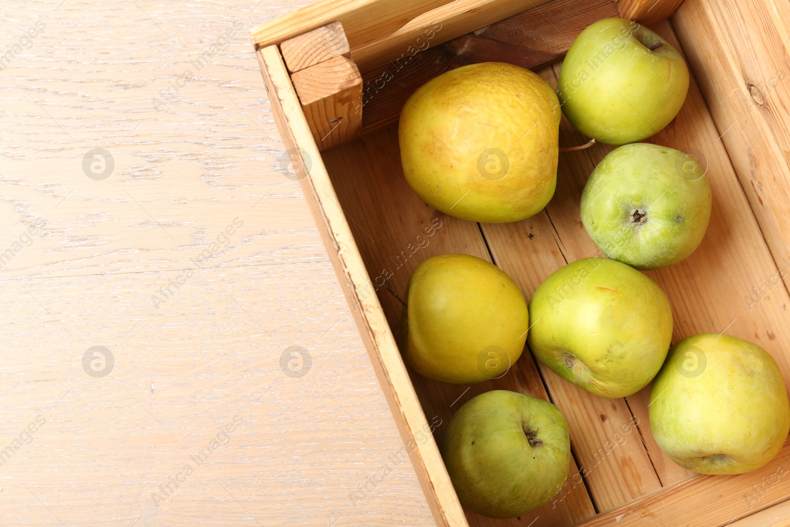 Damaged green apples in wooden crate on table, top view. Space for text Photo of Damaged green apples in wooden crate on table, top view. Space for text
