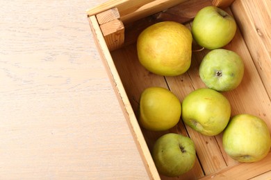 Photo of Damaged green apples in wooden crate on table, top view. Space for text