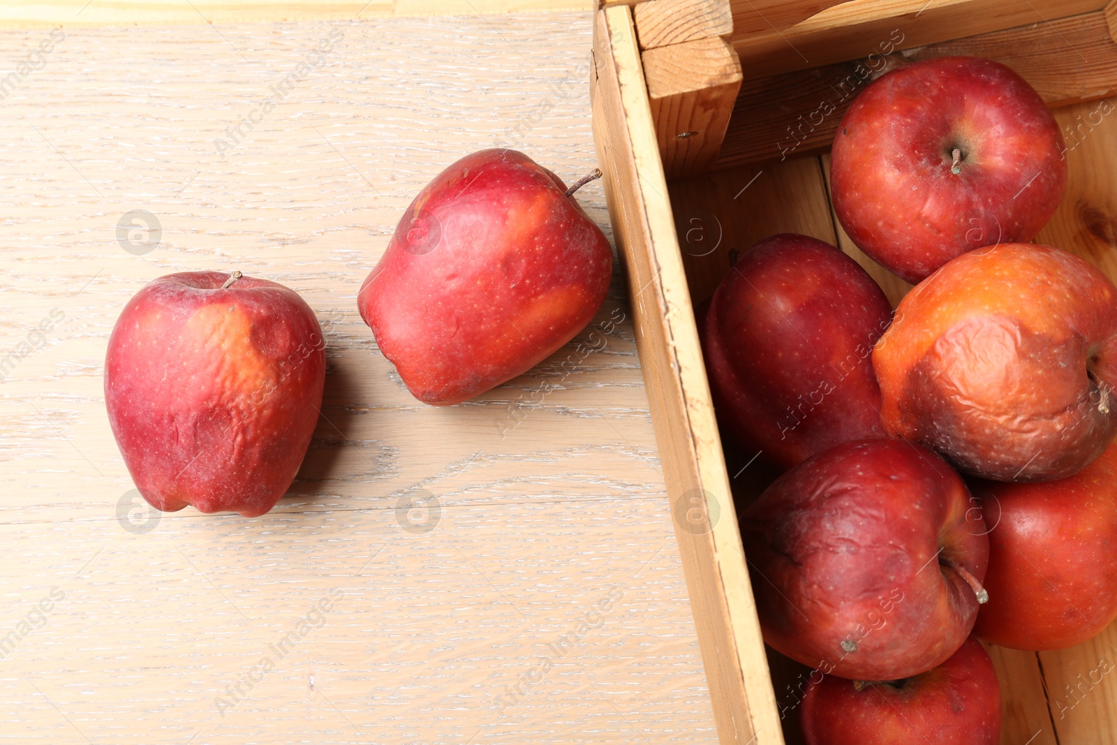 Damaged red apples in wooden crate on table, top view Photo of Damaged red apples in wooden crate on table, top view