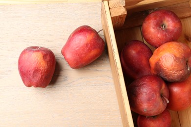 Photo of Damaged red apples in wooden crate on table, top view