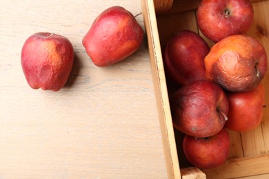 Photo of Damaged red apples in wooden crate on table, top view