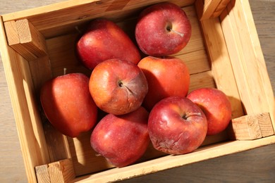 Photo of Damaged red apples in wooden crate on table, top view