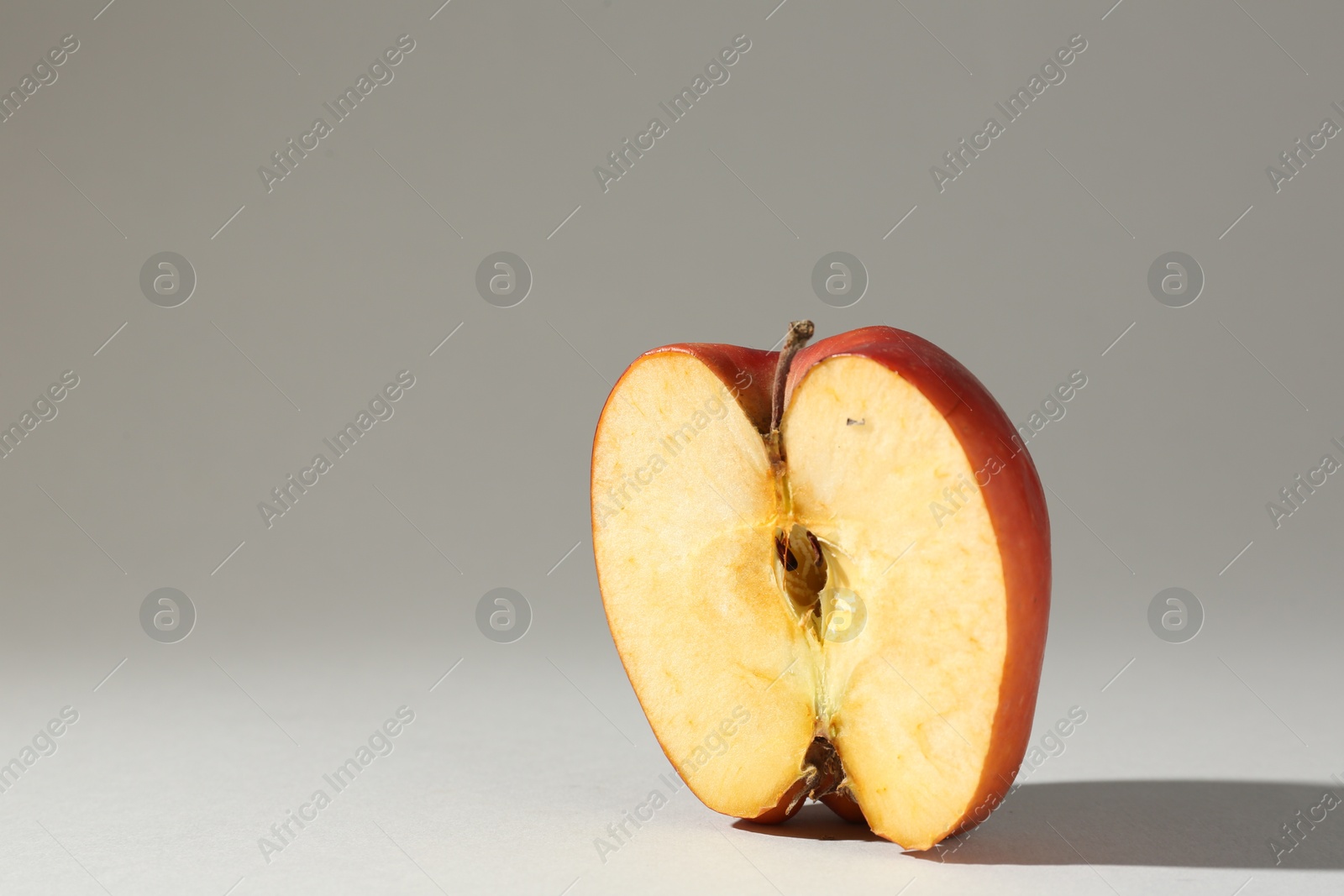 Half of damaged apple on light grey background. Space for text Photo of Half of damaged apple on light grey background. Space for text