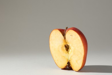 Photo of Half of damaged apple on light grey background. Space for text