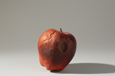 Photo of One rotten red apple on light grey background