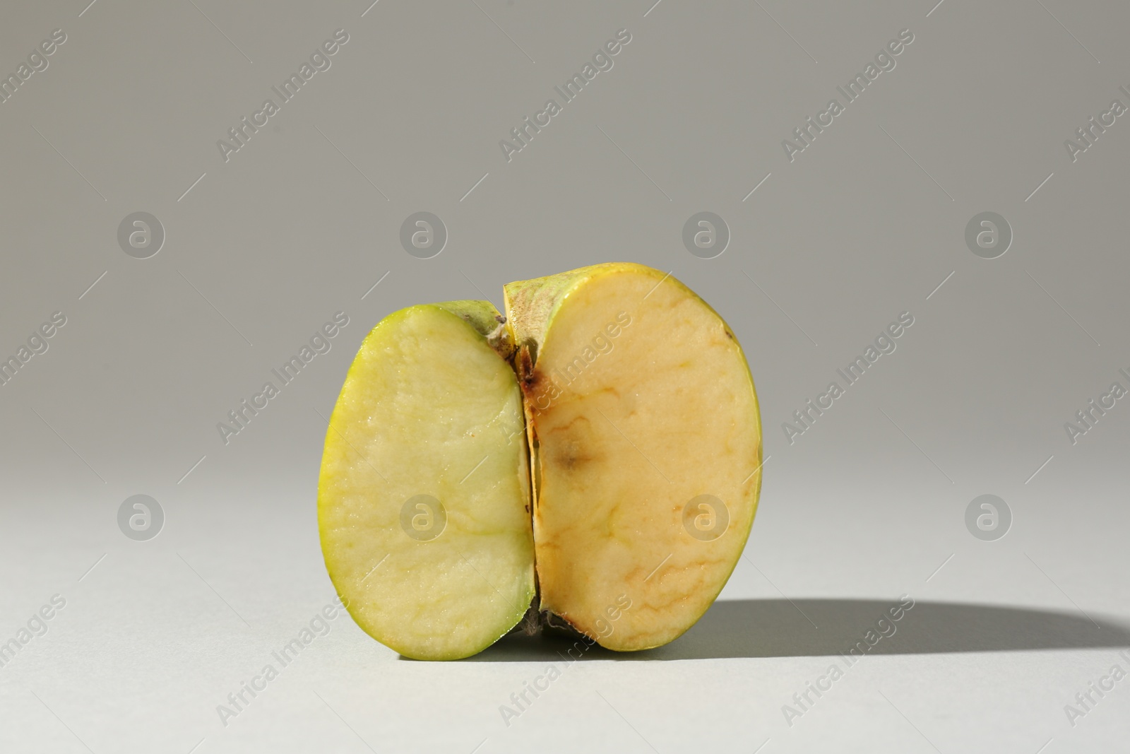 Half of damaged apple on light grey background Photo of Half of damaged apple on light grey background