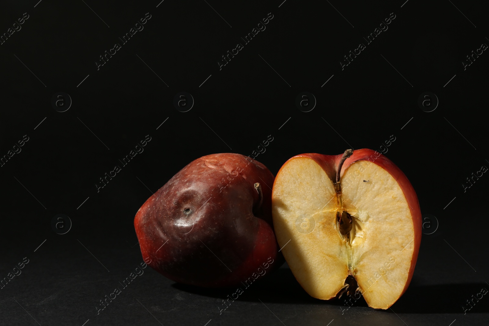 Damaged red apples on black background. Space for text Photo of Damaged red apples on black background. Space for text