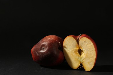 Photo of Damaged red apples on black background. Space for text