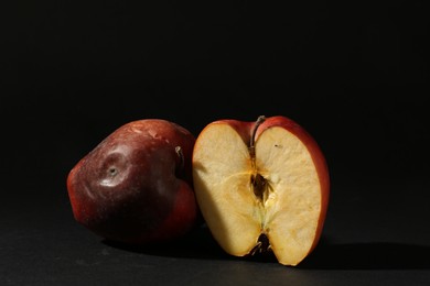 Photo of Damaged red apples on black background. Space for text