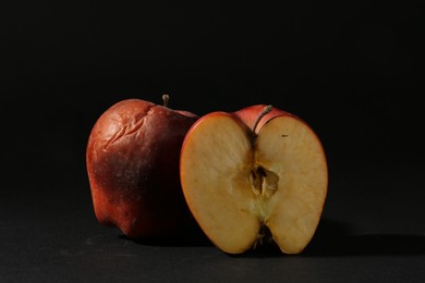 Photo of Damaged red apples on black background, closeup