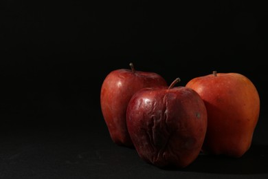 Photo of Damaged red apples on black background. Space for text