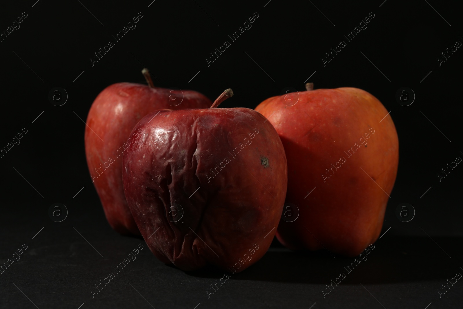 Damaged red apples on black background, closeup Photo of Damaged red apples on black background, closeup