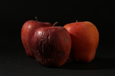 Photo of Damaged red apples on black background, closeup