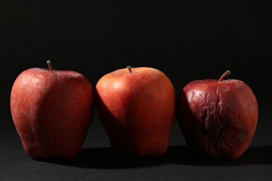 Photo of Damaged red apples on black background, closeup