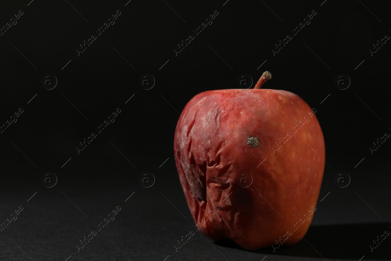 One rotten red apple on black background. Space for text Photo of One rotten red apple on black background. Space for text