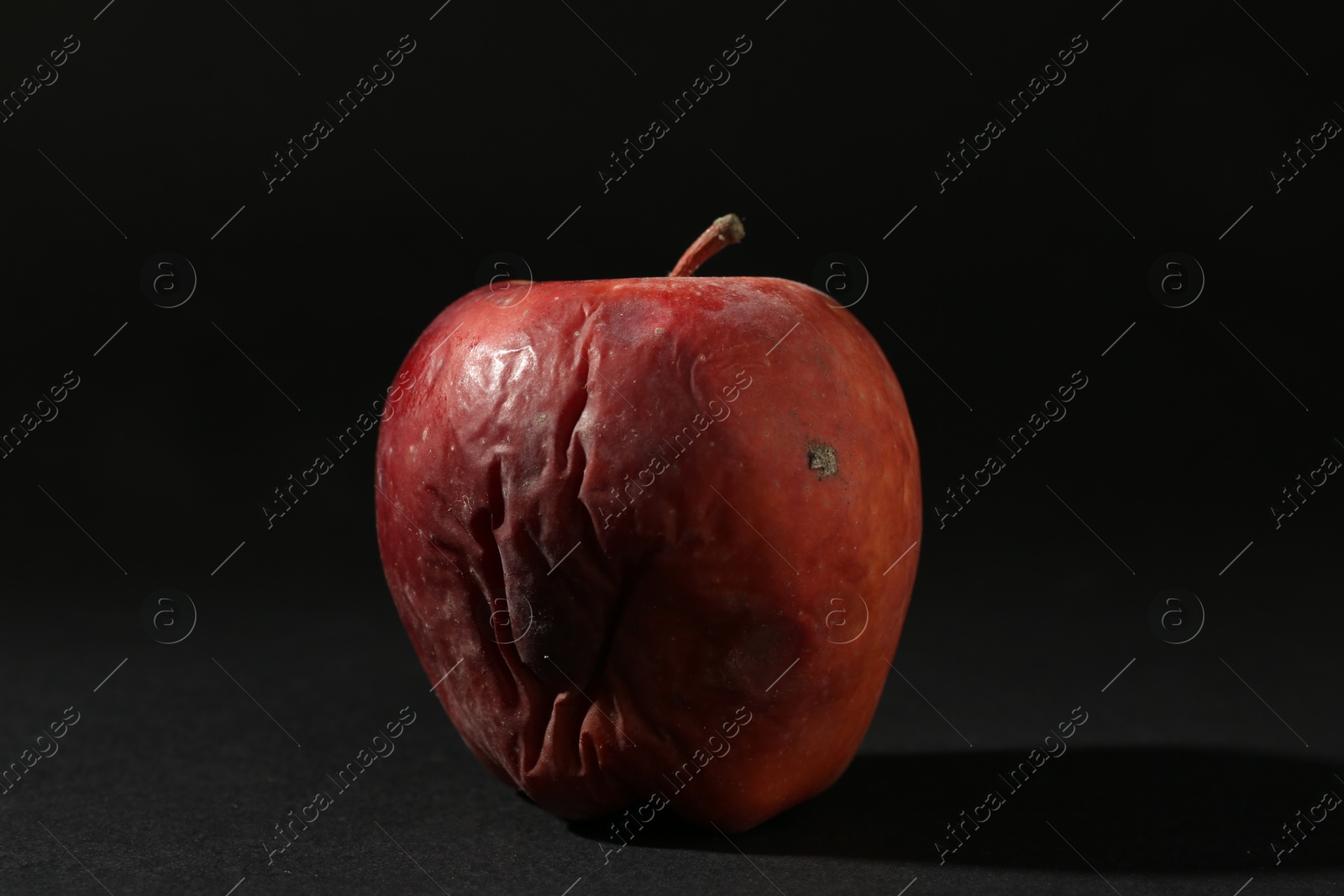 One rotten red apple on black background Photo of One rotten red apple on black background