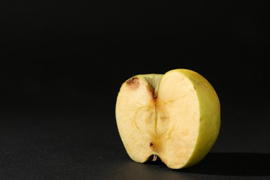 Photo of Half of damaged apple on black background. Space for text