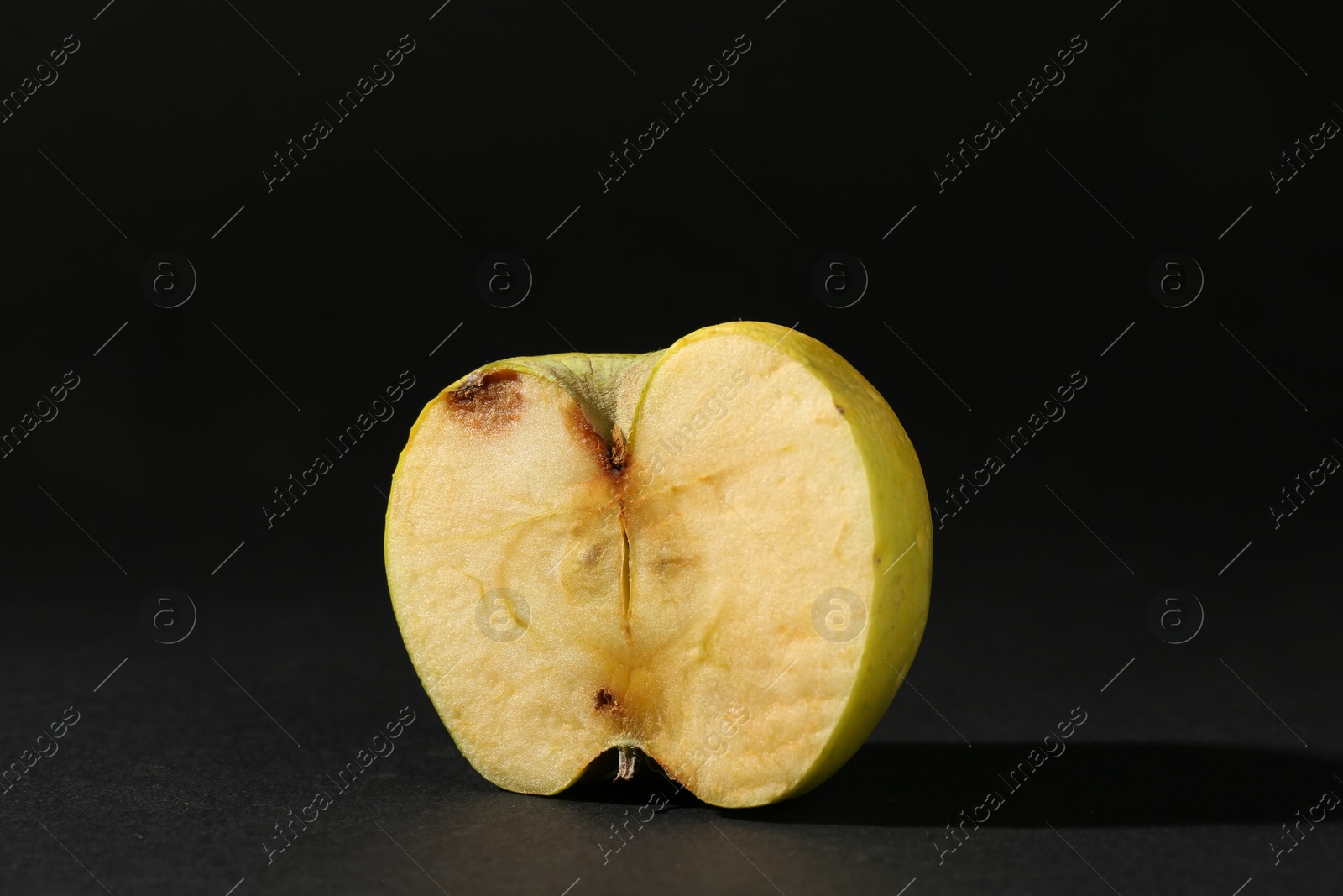 Half of damaged apple on black background Photo of Half of damaged apple on black background