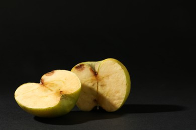 Photo of Halves of damaged apple on black background