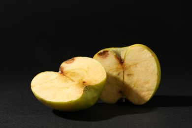 Photo of Halves of damaged apple on black background