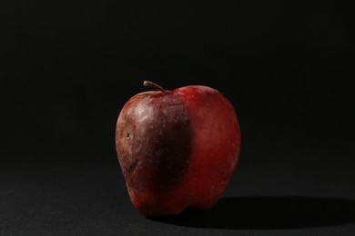 Photo of One rotten red apple on black background