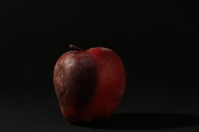 Photo of One rotten red apple on black background
