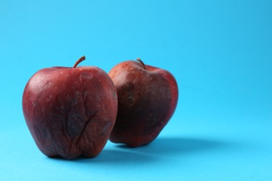 Photo of Damaged red apples on light blue background